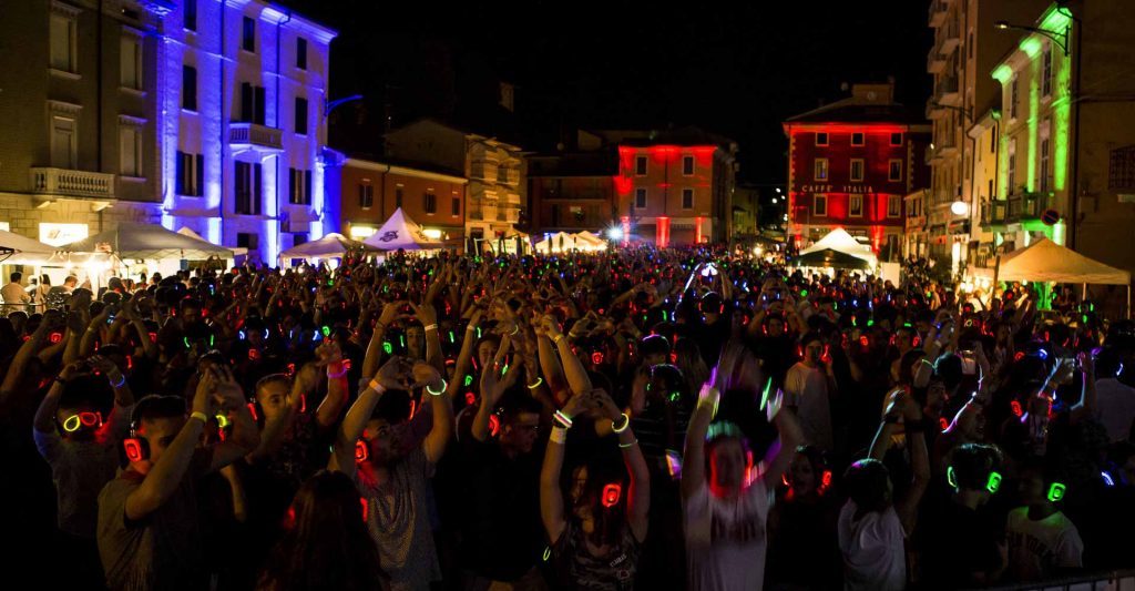 Plaza de noche llena de gente con auriculares de silent disco