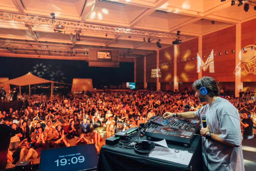 DJ con auriculares de silent disco frente a un gran público con auriculares